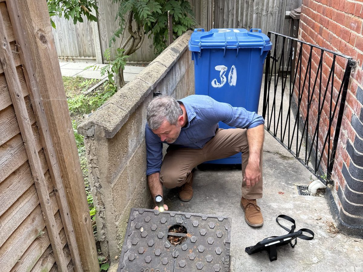 Surveyor inspecting drainage and building services at a property