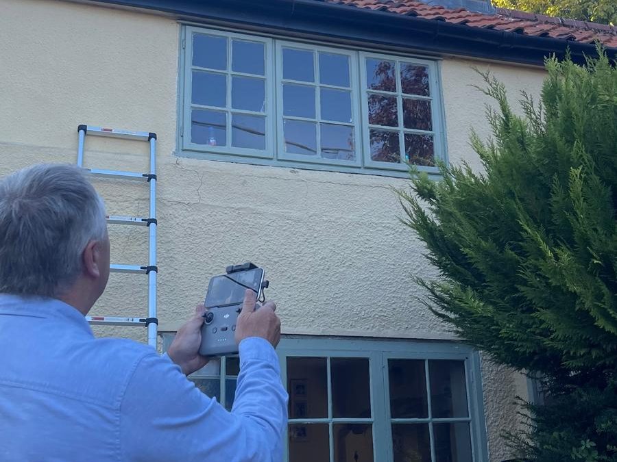 Surveyor inspecting the exterior elevation and windows of a rendered building