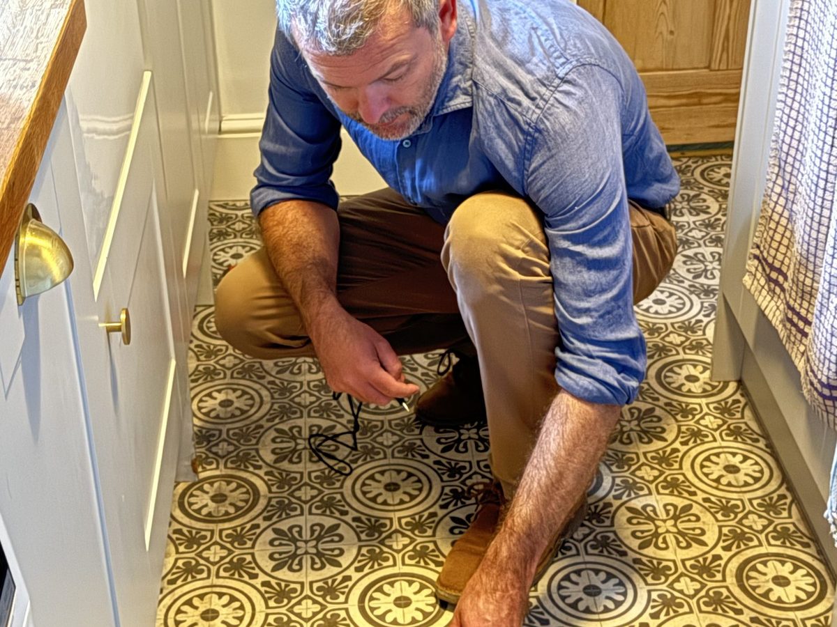 Surveyor taking a moisture reading from a tiled hallway floor