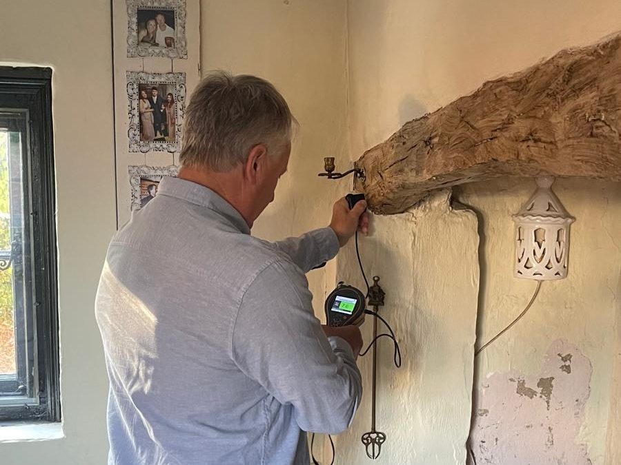 Surveyor checking the condition of a timber beam with a moisture meter