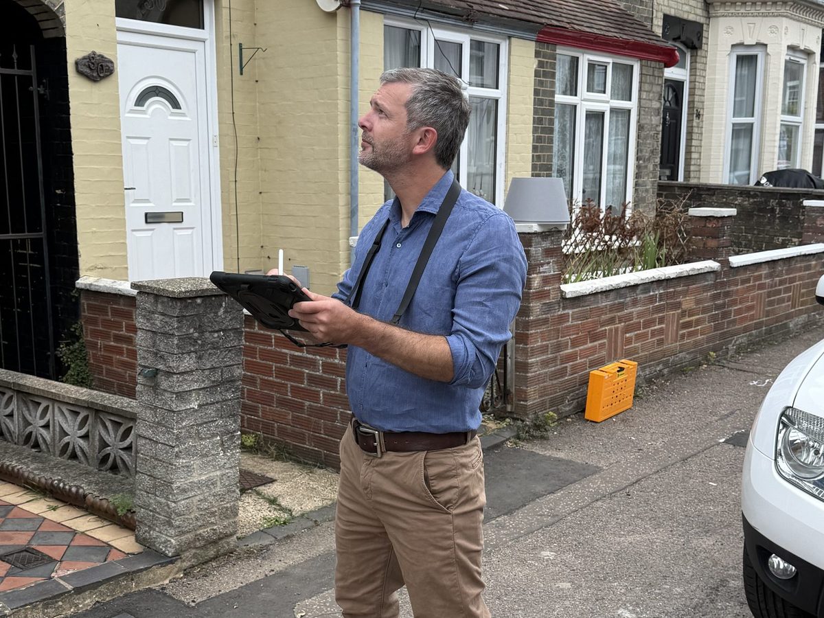 Surveyor assessing the exterior of a well-maintained terraced home