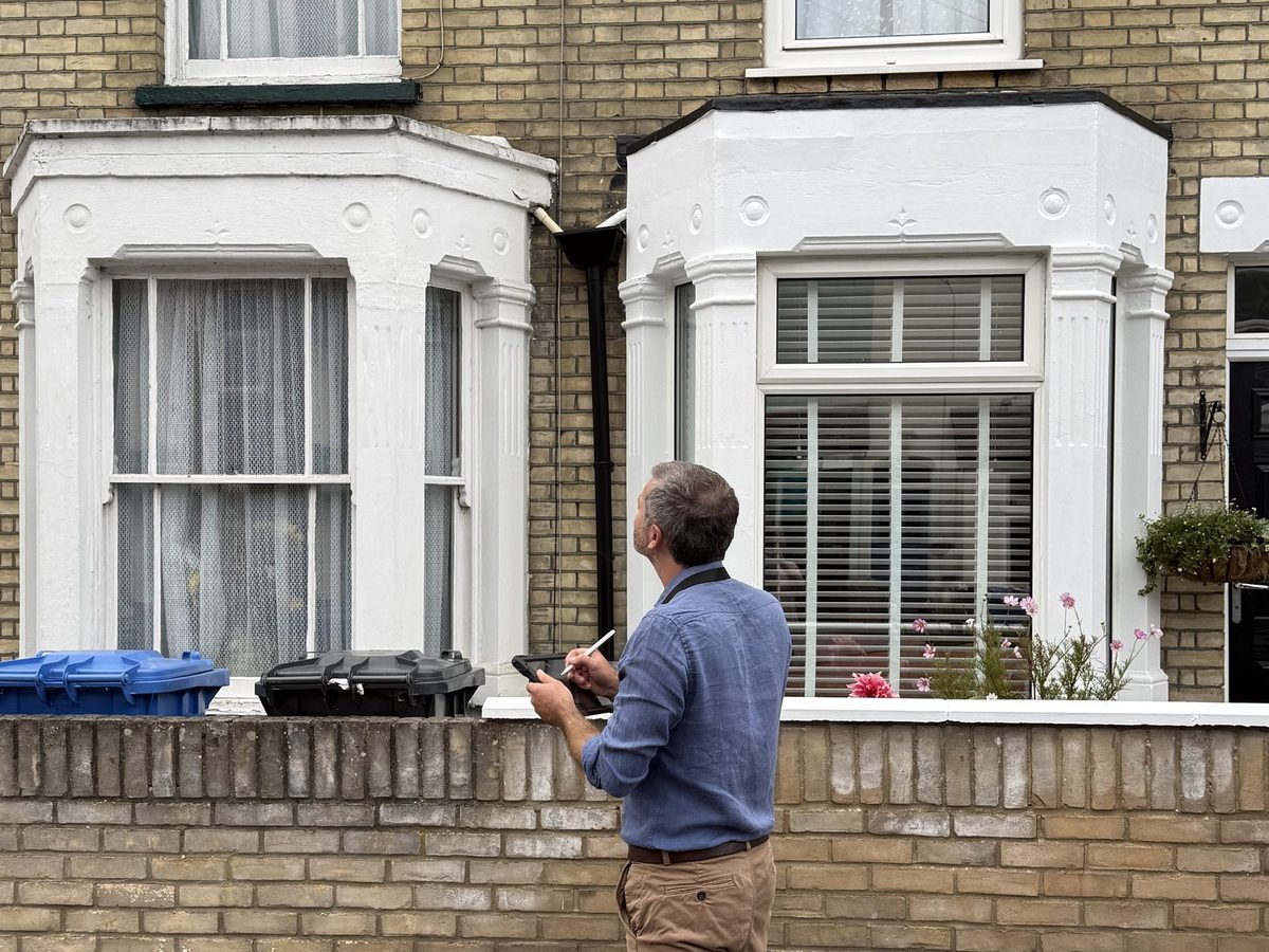 Surveyor inspecting the bay window and external walls of a converted terraced property