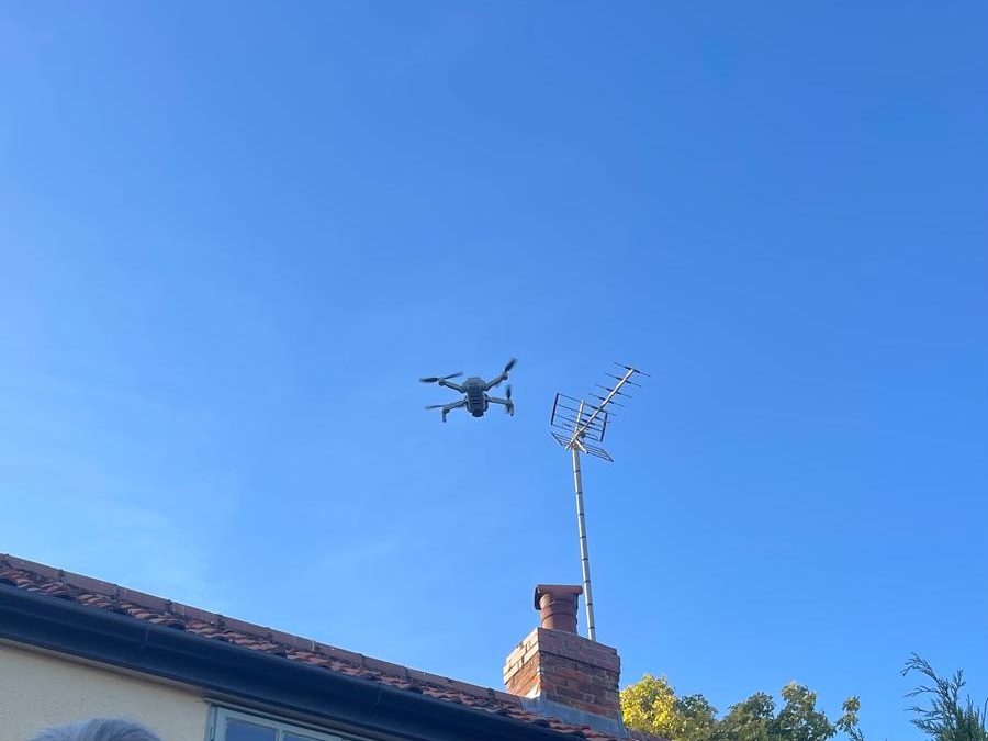 Drone in flight above a roofline during an aerial inspection of a property