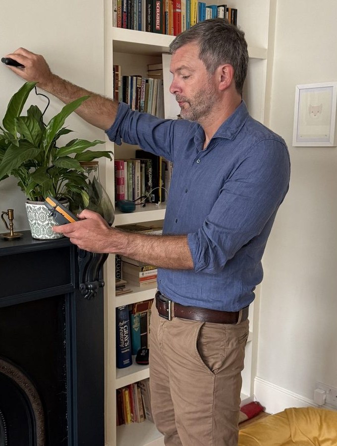 Surveyor examining a chimney breast and alcove during a detailed building survey