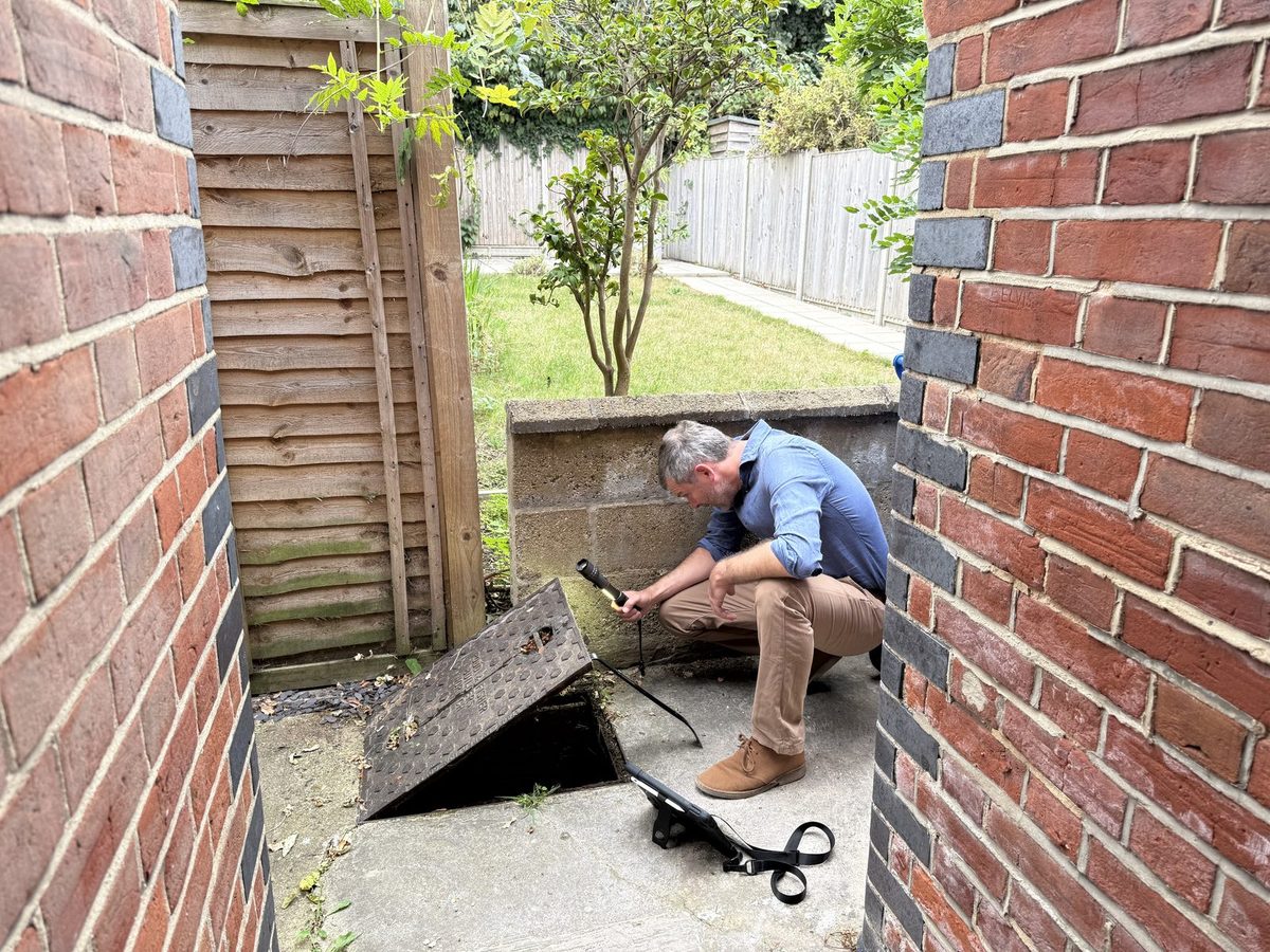 Surveyor checking external works and drainage to the rear of a new property
